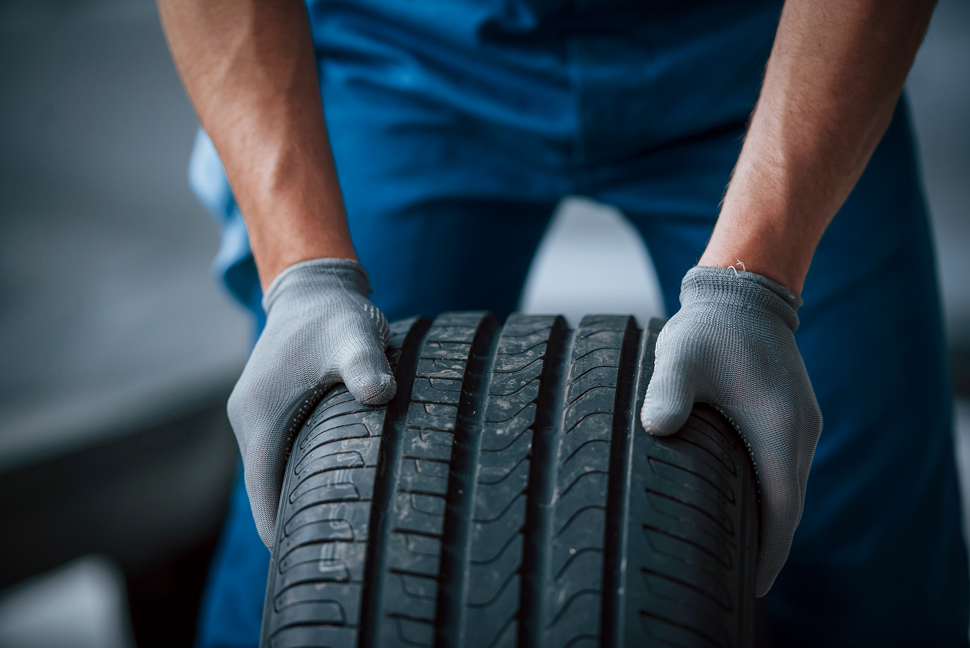 Dirt on the wheel. Mechanic holding a tire at the repair garage. Replacement of winter and summer tires.